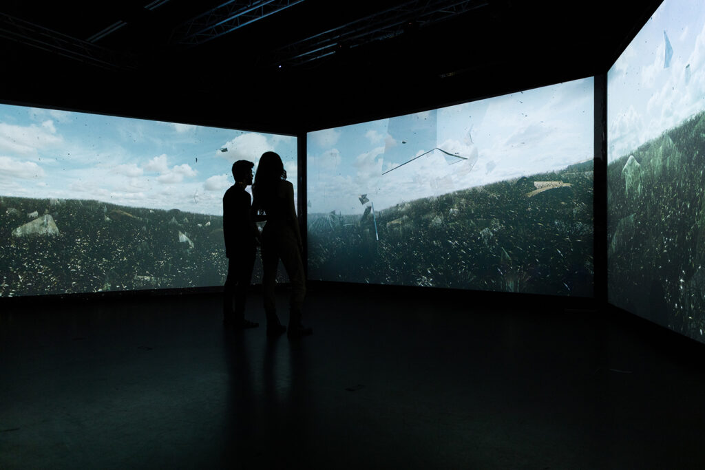 Two persons standing in-front of a very wide screen